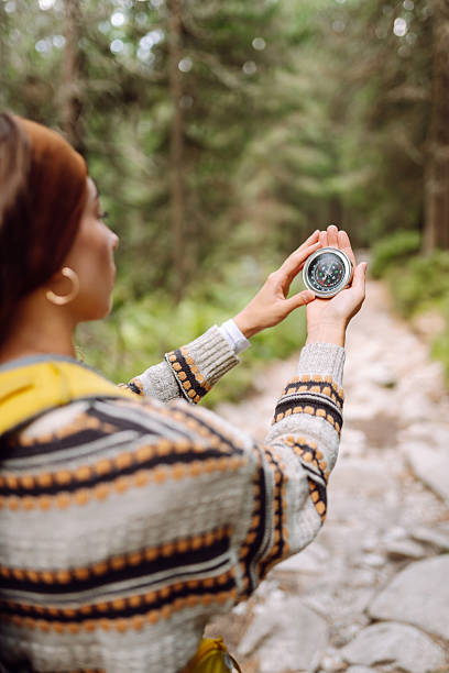 istock Female hiker with backpack holds compass on rocky hiking trail. 2241986353