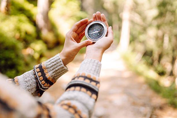 istock Female hiker with backpack holds compass on rocky hiking trail. 2241986354