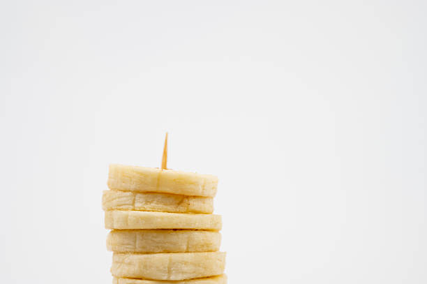 Stacked banana slices with a toothpick on white background.