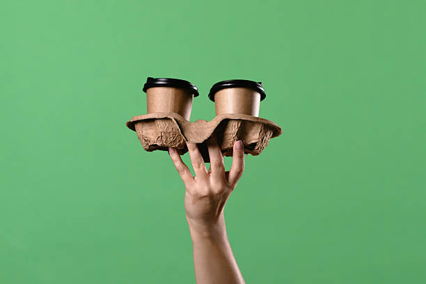 istock Woman Hand Holding Two Coffee Cups with Green Background 2241991410
