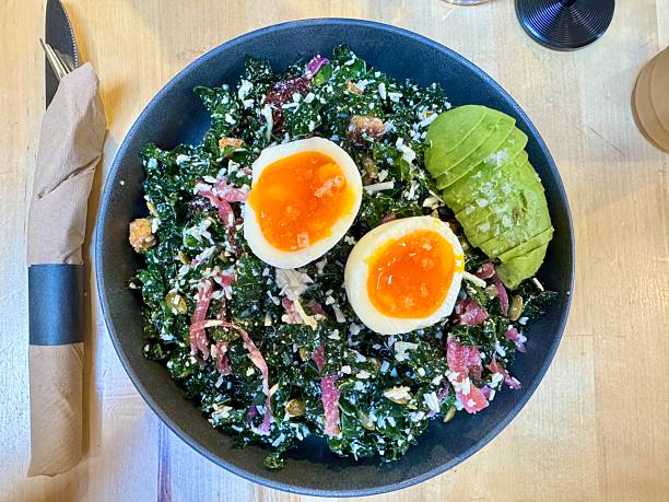 Overhead view of chopped kale salad with boiled egg and sliced avocado at a restaurant in Philadelphia, PA