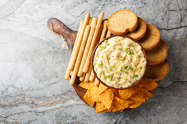 istock Deviled Egg Dip appetizer for a buffet or picnic with nachos, breadsticks and toast close-up on a wooden board. Horizontal top view 2241999735