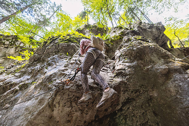 Young woman organizes climbing gear below cliff face