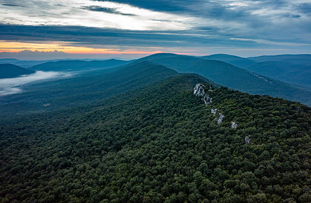 Aerial view of Big Schloss on Great North Mountain at dawn, on the Virginia/West Virginia border. Mist fills the forested valleys as soft sunrise light reveals the rocky ridgeline.