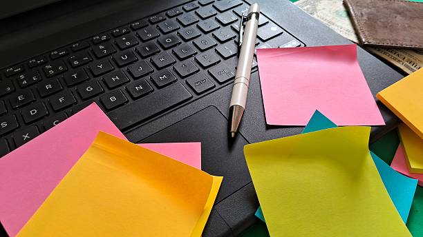 istock Desk essentials with laptop, colorful post-its, pen and leather wallet with dollars inside on green background 2242001677