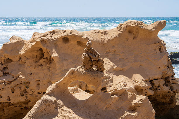 Whimsical white and sandy rock formations on the coast against the backdrop of a turquoise-blue sea and a clear blue sky.