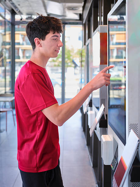 istock Teenager using self-service kiosk to order fast food 2242016658