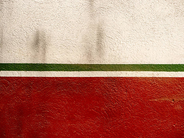 wall features bold red and white sections with green stripe running horizontally. colors create striking contrast. Natural light casts soft shadows, adding depth to textured surface