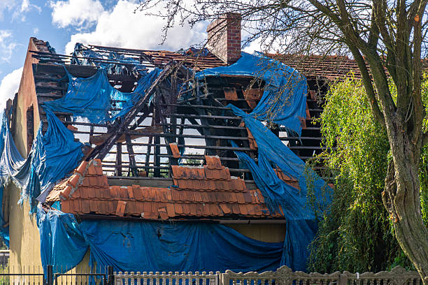 Severely damaged house roof, wooden structure exposed, clearly visible aftermath of a fire incident.