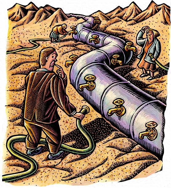man stands next to pipeline in the desert holding a hose, many faucets
