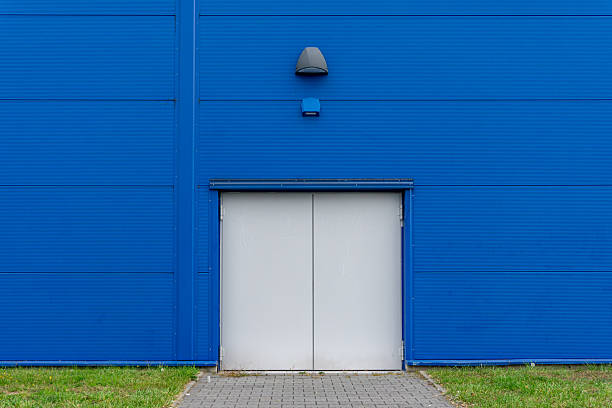 istock Gray technical door in blue industrial building facade, minimalist architecture, simple exterior wall, service entrance, geometric lines and modern construction structure 2242019747