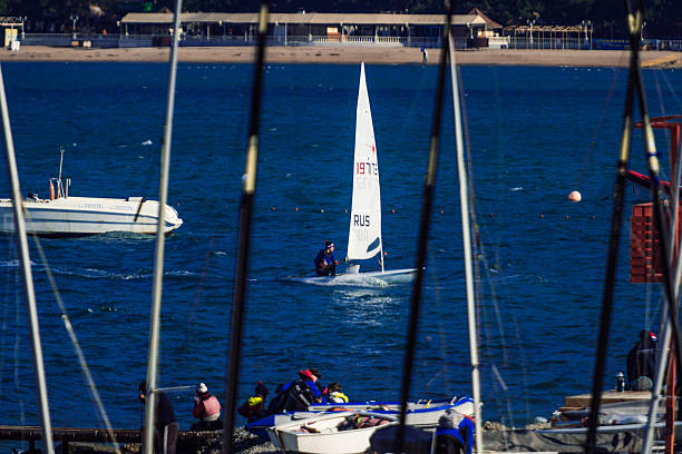 A sailboat with the name Ette on it is sailing in the ocean. The scene is peaceful and serene, with several other boats in the background