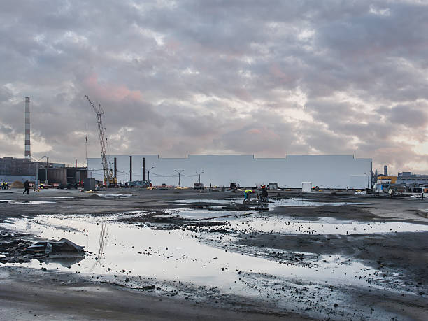 istock Industrial construction site under a cloudy sky with a crane and workers. 2242030045