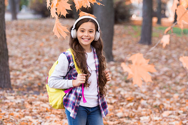 istock smiling child carry backpack and listen music, school time 2242030363