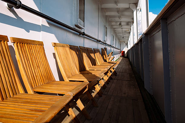 Neatly arranged wooden chairs on sunny ship deck corridor, creating calm maritime travel atmosphere, sea transport, nautical lifestyle