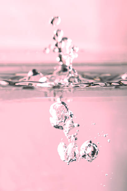 A drop of water is captured hitting a liquid abstract surface.