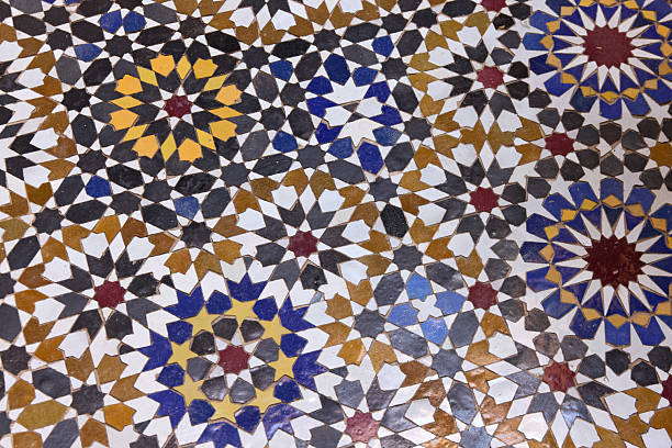 A detailed Islamic geometric mosaic featuring vibrant colors and symmetrical patterns. The design showcases traditional arabesque motifs with star shapes and interwoven lines