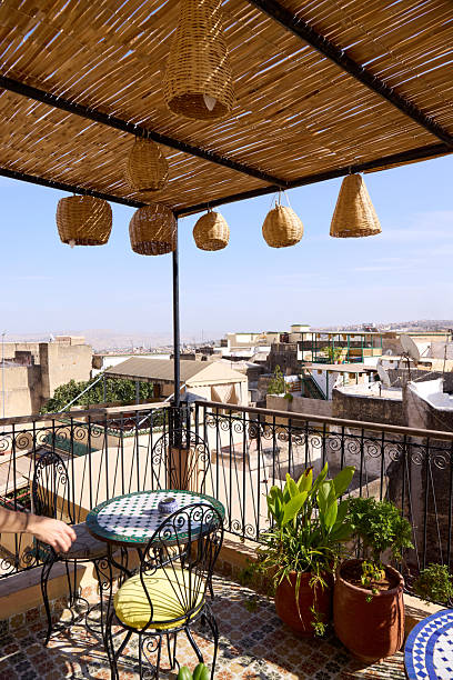 istock A cozy terrace in Morocco welcomes relaxation with a small table and chairs surrounded by lush plants. The view captures rooftops under a bright blue sky, inviting visitors to unwind 2242044892