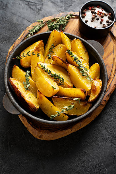 istock Roasted sliced potatoes with thyme herb, salt, peppers, cut board 2242049325