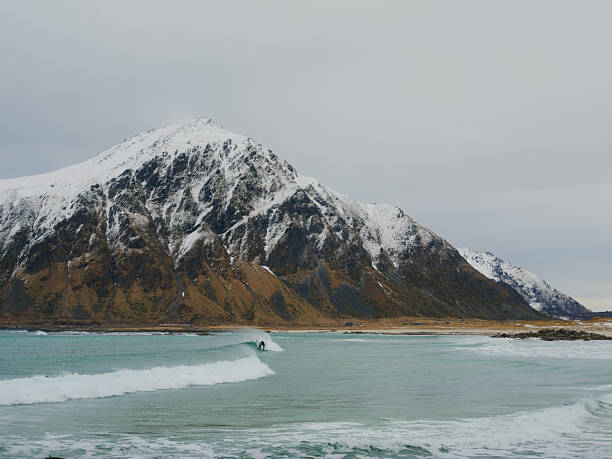 Man surfing on the beach on Lofoten islands in Norway in winter
