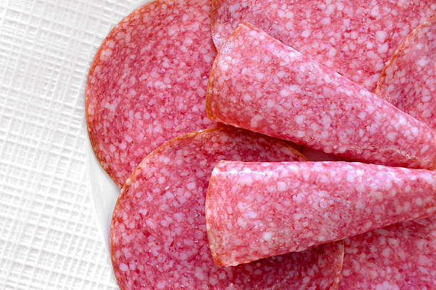 Salami smoked sausage slices in a white plate. Italian food.