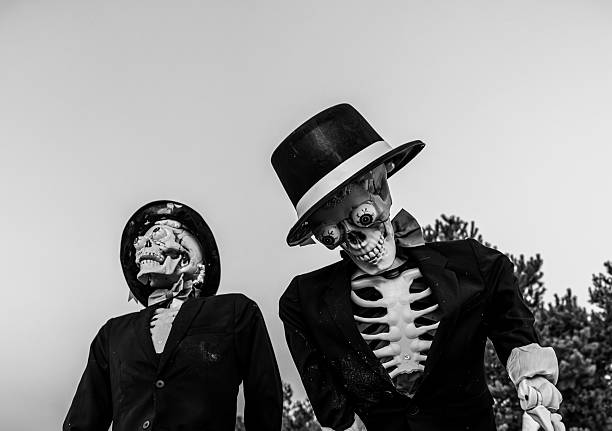 Two decorative skeletons dressed in suits and hats for Halloween. Perfect spooky and festive autumn decoration for parties, events, or holiday stock content.
