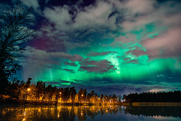 Autumn view of the northern lights (aurora borealis) above a lake in Southern Finland. The aurora reflects beautifully on the water, creating a magical and serene evening scene.