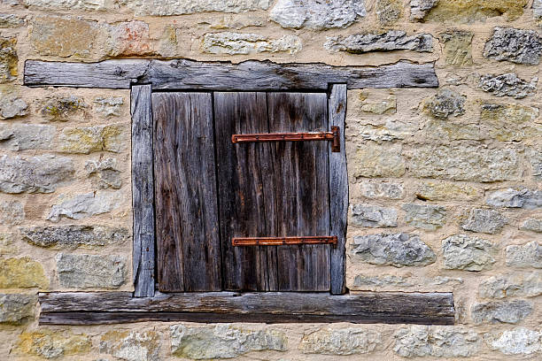 Old wooden window frame and closed shutter in a stone wall