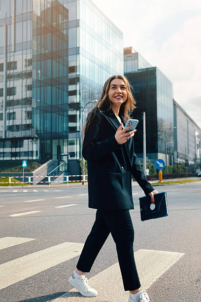 istock Professional Woman Walking Confidently in a Business District While Using Her Smartphone on a Sunny Day During Work Hours 2242068304
