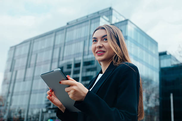istock Young Professional Engages With Tablet While Standing in Front of Modern Buildings on a Cloudy Day in an Urban Environment 2242068314