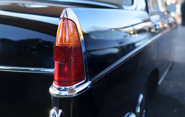istock Classic black vintage car tail light close-up with chrome details and sunlight reflection 2242070140