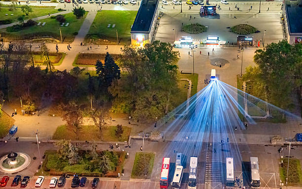 Nighttime cityscape with building highlighted by vibrant laser lights from above.