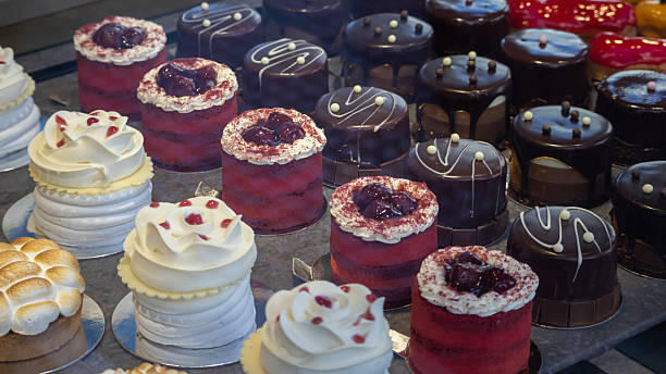 delightful assortment of decadent mini cakes including red velvet, chocolate mousse, and meringue, displayed in a bakery window. perfect sweet treat