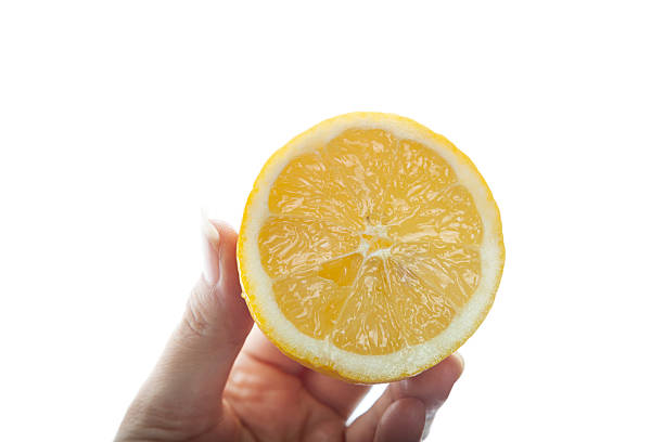 Female hand holding a fresh lemon cut in half on a white background