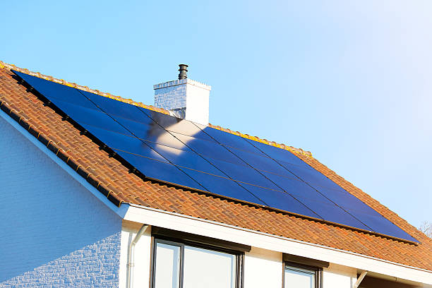 istock Solar panels cover a terracotta tiled rooftop under bright sunlight and clear blue sky. 2242082045