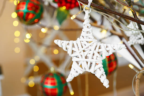 Decorative ornament for Christmas tree star shape with branches and berries on bright lights, bokeh background, holiday atmosphere Christmas and New Year holidays. Backdrop, wallpaper