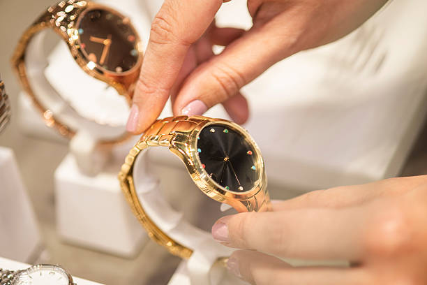 Woman's hands placing female wristwatches on display in a store