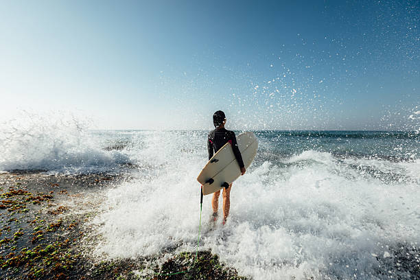 Woman surfer with surfboard going to surf at seaside