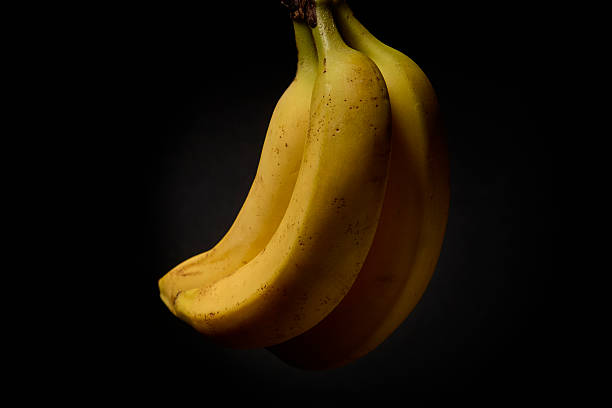 istock Bunch of bananas in elegant dark studio lighting 2242090299