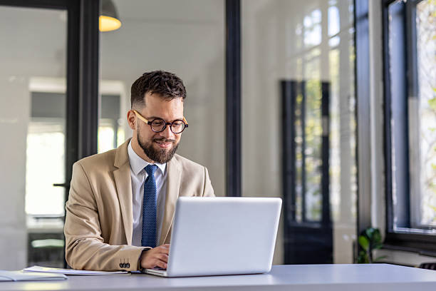 istock Professionally Dressed Man Working on a Laptop in Office 2242090338