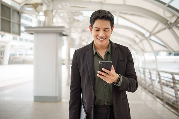 istock Successful businessman smiling while holding his smartphone and walking in a modern city walkway. 2242091483