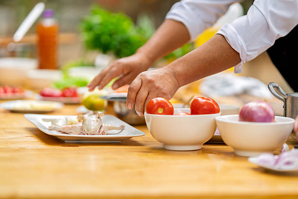 Chef's hands preparing a traditional peruvian dish outdoors, featuring a whole guinea pig and fresh vegetables on a wooden table
