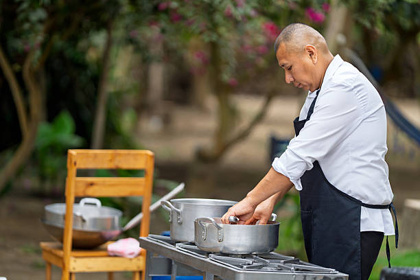 Man chef cooking food outdoors for a country restaurant, preparing a healthy meal with fresh ingredients