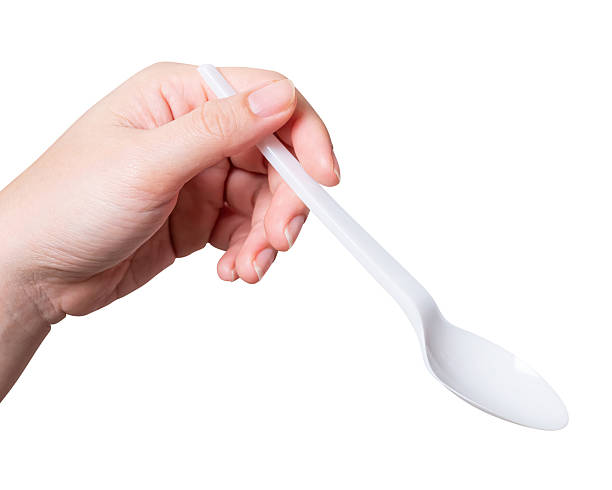 istock Female hand holding a white plastic spoon isolated on white background. 2242097183