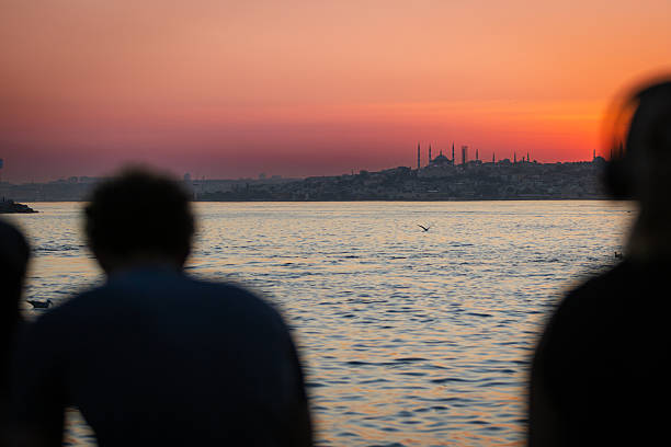 istock People silhouette, looking at Istanbul cityscape view at sunset. 2242097567