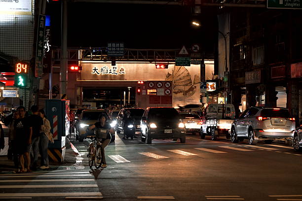 Taiwan - Oct.  11, 2025: Busy urban intersection at night in Dadaocheng District, Taipei, with vehicles, pedestrians, traffic lights, and elevated expressway overhead.