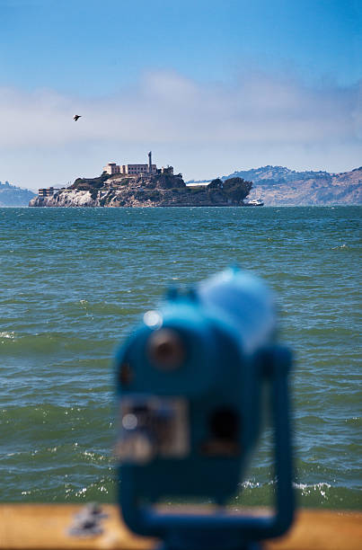San Francisco, United States - November 25, 2022: A picture of Alcatraz Island and the surrounding San Francisco Bay, with a water taxi sailing near the foreground.