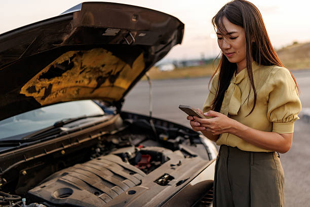 istock Frustrated Asian Woman Stranded Beside Her Broken Car, Calling for Roadside Assistance on Smartphone 2242102238