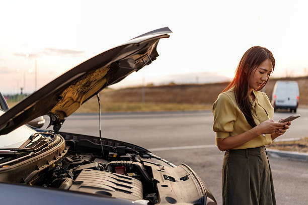 istock Stressed Asian woman using smart phone to call roadside assistance after car breakdown on quiet rural road 2242102344