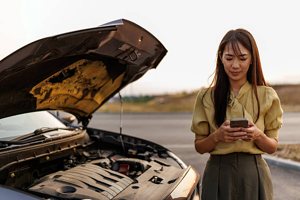 istock Stressed Asian woman using smart phone to call roadside assistance after car breakdown on quiet rural road 2242102413